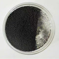 Spherical activated carbon beads, black, in a glass dish on white background